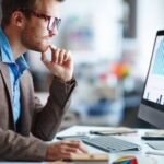 46622394-male-office-worker-looking-at-computer-screen-with-data